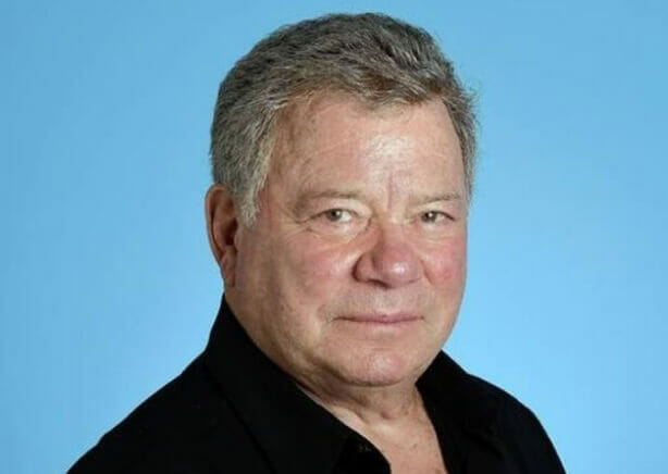 William Shatner standing against a light blue background commenting on Martin’s books.